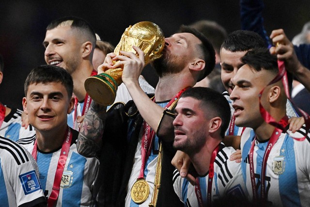 Pemain Argentina Lionel Messi memegang trofi Piala Dunia saat berselebrasi bersama rekan setimnya setelah memenangkan Piala Dunia 2022, di Stadion Lusail, Lusail, Qatar, Minggu (18/12/2022). Foto: Dylan Martinez/REUTERS
