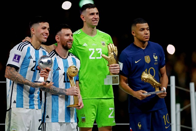 Pemain Argentina Lionel Messi bersama kiper Argentina Emiliano Martinez, pemain Prancis Kylian Mbappe, dan pemain Argentina Enzo Fernandez berpose dengan trofi di Stadion Lusail, Lusail, Qatar, Minggu (18/12/2022). Foto: Hannah McKay/REUTERS