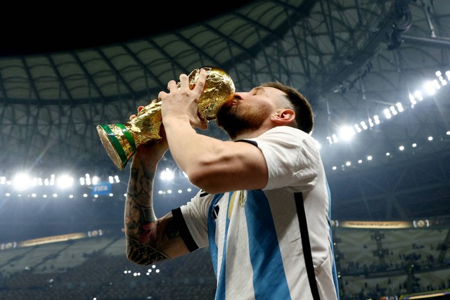 Pemain Argentina Lionel Messi mencium trofi Piala Dunia saat berselebrasi setelah memenangkan Piala Dunia 2022, di Stadion Lusail, Lusail, Qatar, Minggu (18/12/2022). Foto: Hannah McKay/REUTERS