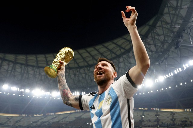 Pemain Argentina Lionel Messi memegang trofi Piala Dunia saat berselebrasi setelah memenangkan Piala Dunia 2022, di Stadion Lusail, Lusail, Qatar, Minggu (18/12/2022). Foto: Hannah McKay/REUTERS