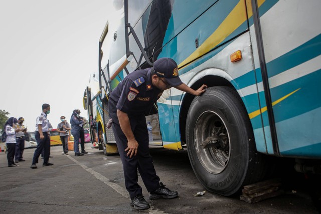Petugas memeriksa kondisi ban bus saat melakukan pemeriksaan kelaikan kendaraan (ramp check) di Terminal Kalideres, Jakarta, Senin (19/12/2022). Foto: Fauzan/ANTARA FOTO
