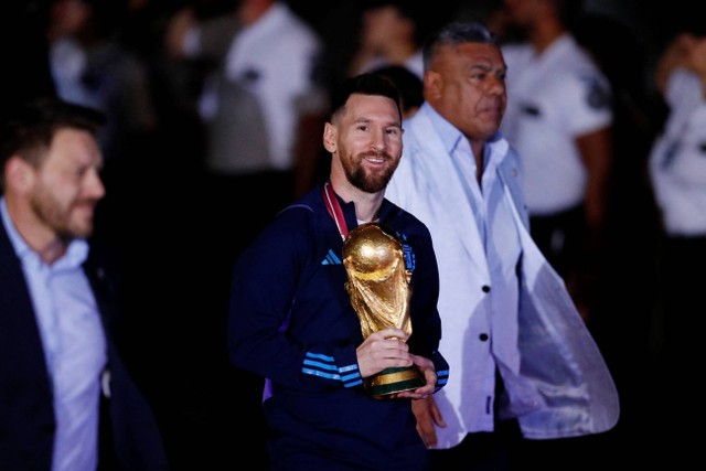 Pemain Argentina Lionel Messi membawa trofi juara Piala Dunia 2022 saat tiba di Bandara Internasional Ezeiza, Buenos Aires, Argentina, Selasa (20/12/2022). Foto: Agustin Marcarian/REUTERS