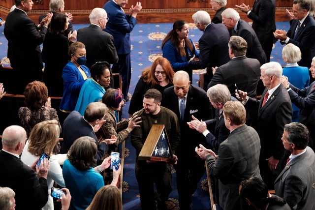 Presiden Ukraina Volodymyr Zelensky berjalan setelah menerima bendera AS dari Ketua DPR AS Nancy Pelosi selama pertemuan bersama Kongres AS di Kamar Dewan Capitol AS di Washington, AS, Rabu (21/12/2022). Foto: Michael McCoy/REUTERS