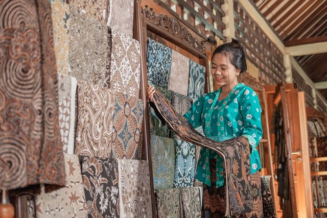 Ilustrasi perempuan memilih kain batik. Foto: Shutterstock