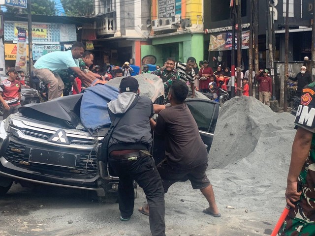 Warga membantu efakuasi mobil Pajero Sport yang tertimpa Truk pasir di Jalan Alternatif Cibubur. Foto: Rinjani Meisa/kumparan