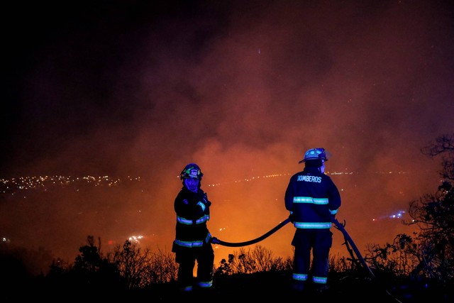 Petugas pemadam kebakaran bekerja saat kebakaran hutan memengaruhi perbukitan Vina del Mar, tempat ratusan rumah berada, di Wilayah Valparaiso, Chile, pada Jumat (23/12/2022). Foto: Javier Torres/AFP