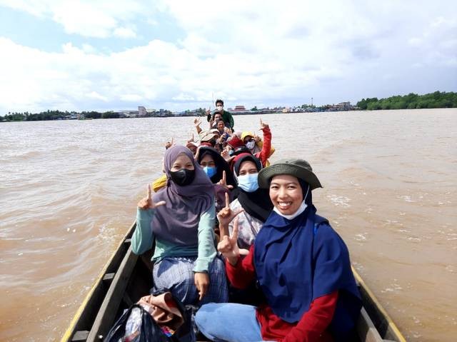 Badar bersama volunter Kampung Baca Tansal menggunakan perahu untuk memudahkan anak-anak mengakses buku. Foto: Dok. Pribadi