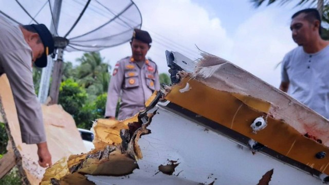 Tampak anggota kepolisian memeriksa sebuah puing mirip badan pesawat yang ditemukan warga pesisir Pantantai Air Danau, Sejuba, Desa Sepempang, Natuna, Kepri, Sabtu (24/12). Foto: ANTARA/Cherman