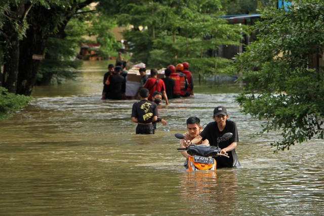 Warga menuntun sepeda motornya melewati banjir di Perumnas Antang, Makassar, Sulawesi Selatan, Senin (26/12/2022). Foto: Arnas Padda/ANTARA FOTO