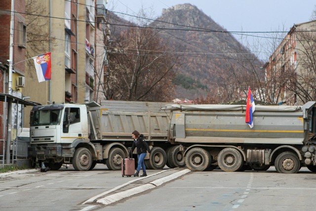 Warga berjalan di dekat kendaraan yang memblokade jalan di bagian utara kota Mitrovica, Kosovo. Foto: Florion Goga/REUTERS