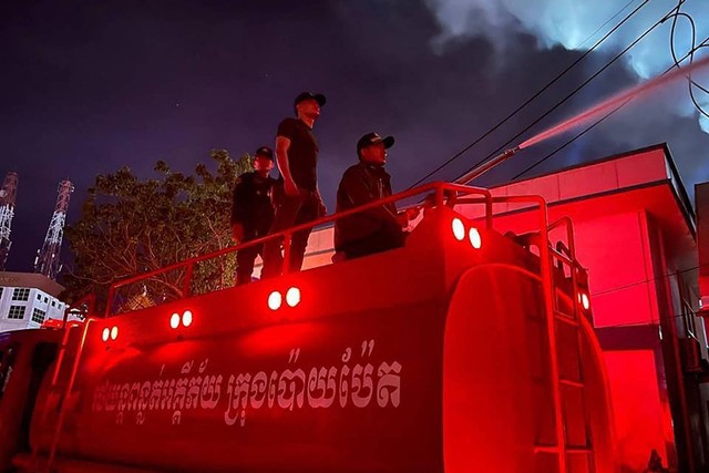 Petugas pemadam kebakaran menyemprotkan air ke api di kasino hotel Grand Diamond City di Poipet, Kamboja, Thailand, Kamis (29/12/2022). Foto: STR/AFP