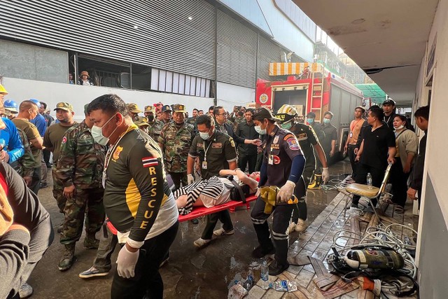 Petugas penyelamat membawa orang yang terluka dengan tandu di lokasi kebakaran di kasino hotel Grand Diamond City di Poipet, Kamboja, Thailand, Kamis (29/12/2022). Foto: STR/AFP