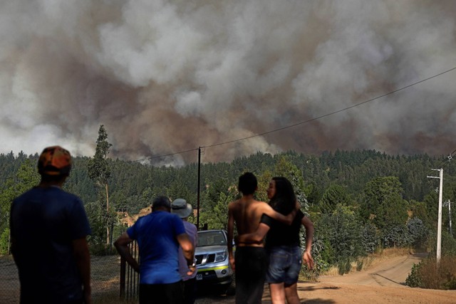 Penduduk setempat berkumpul dan menyaksikan kebakaran hutan membakar sebagian daerah pedesaan di sekitar Santa Juana, Chili, akibat gelombang panas, 30 Desember 2022.  Foto: Juan Gonzalez/REUTERS