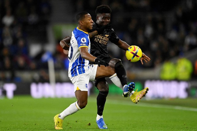 Pemain Brighton & Hove Albion Pervis Estupinan beraksi dengan pemain Arsenal Bukayo Saka di Stadion Komunitas American Express, Brighton, Inggris, Sabtu (31/12/2022). Foto: Tony Obrien/REUTERS