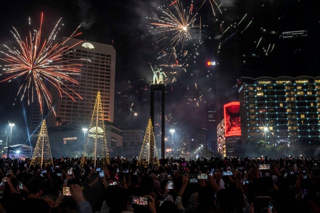 Sejumlah warga menyaksikan pesta kembang api menyambut tahun baru 2023 di kawasan Bundaran HI, Jakarta, Minggu (1/1/2023). Foto: Aprillio Akbar/ANTARA FOTO