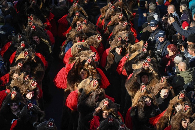 Orang-orang yang mengenakan kostum kulit beruang terlihat berbaris selama Parade Kulit Beruang di Comanesti, Rumania, Jumat (30/12/2022). Foto: Daniel Mihailescu/AFP