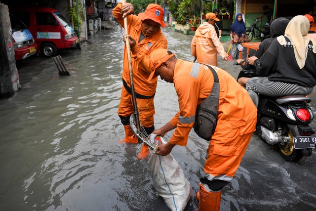 Petugas Penanganan Prasarana & Sarana Umum (PPSU) menjaring sampah saat terjadinya banjir di kawasan Semper Barat, Jakarta Utara, Minggu (1/1/2023). Foto: M Risyal Hidayat/Antara Foto 