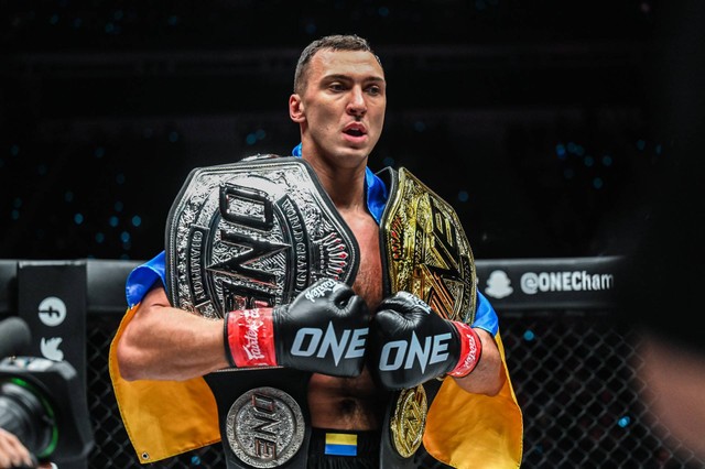 Roman Kryklia berpose dengan dua sabuk Juara Dunia ONE Championship usai mengalahkan Iraj Azizpour. Foto: ONE Championship