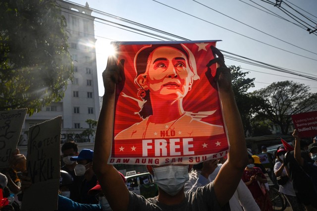 Seorang pengunjuk rasa mengangkat poster yang menampilkan Aung San Suu Kyi saat demonstrasi menentang kudeta militer di depan Bank Sentral Myanmar di Yangon. Foto: STR/AFP