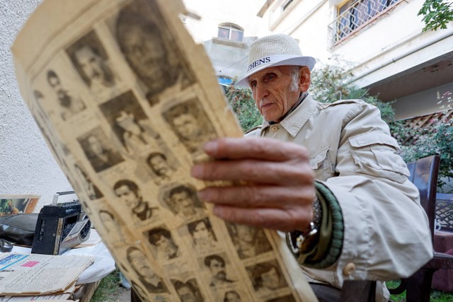 Talal Taha membaca koran di rumahnya di Gaza. Foto: Mohammed Salem/REUTERS