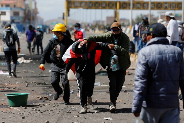 Seorang demonstran membantu seorang pria yang terluka dalam bentrokan dengan pasukan keamanan, di dekat bandara Juliaca, di Juliaca, Peru, Senin (9/1/2023). Foto: Hugo Courotto/Reuters