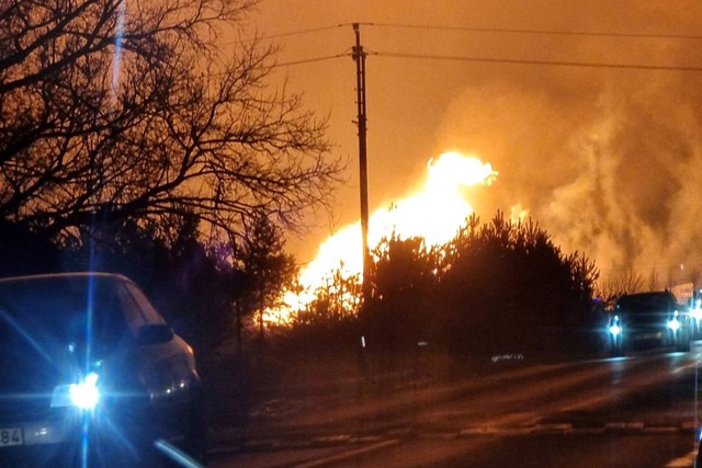 Kendaraan layanan darurat terlihat sebagai kobaran api dari pipa gas yang terbakar setelah ledakan, di Pasvalys, Lituania, Jumat (13/1/2023). Foto: Gintautas Geguzinskas/via REUTERS