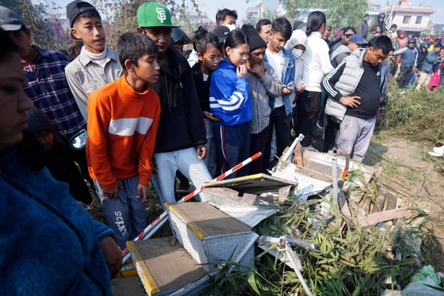 Warga melihat tim penyelamat mengevakuasi korban jatuhnya pesawat Yeti Airlines di Pokhara, Nepal, Minggu (15/1/2023).  Foto: Bijay Neupane/via REUTERS