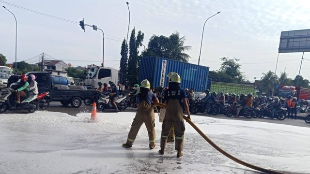 Damkar bantu membersihkan oli tumpah di Jalan Raya Kebon Baru, Cilincing, Jakarta Utara, Senin (16/1/2023). Foto: Sudin Gulkarmat Jakut