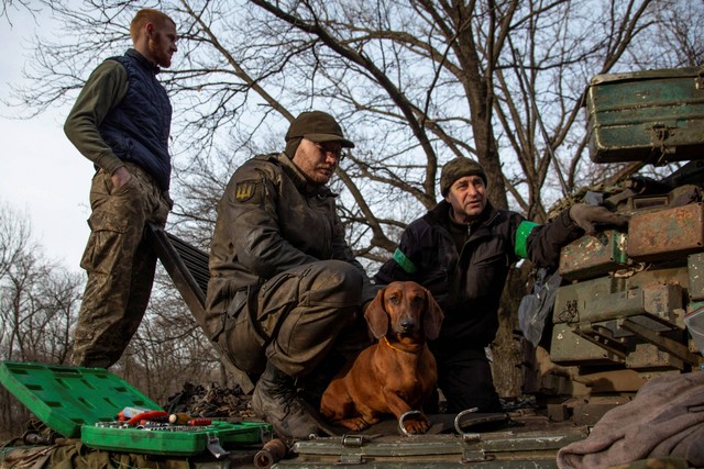 Seekor anjing bernama Chip duduk di sebelah prajurit Ukraina yang memperbaiki tank di kota Bakhmut Ukraina, Jumat (20/1/2023). Foto: Oleksandr Ratushniak/Reuters