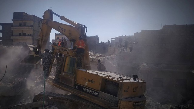 Pekerja dengan menggunakan alat berat melakukan evakuasi runtuhnya bangunan tempat tinggal di kawasan Sheikh Maksoud di Aleppo, Suriah. Foto: SHAM FM/via REUTERS