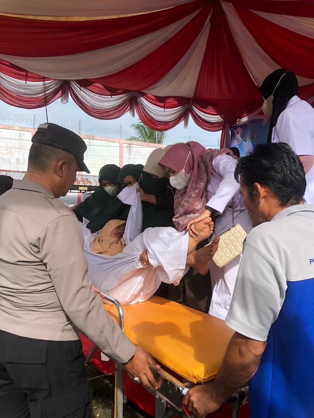 Petugas mengevakuasi perempuan terpidana kasus jarimah zina yang pingsan usai menjalani hukuman cambuk 100 kali di halaman Lapas Meulaboh, Aceh Barat, Selasa (24/1/2023). Foto: Siti Aisyah/acehkini