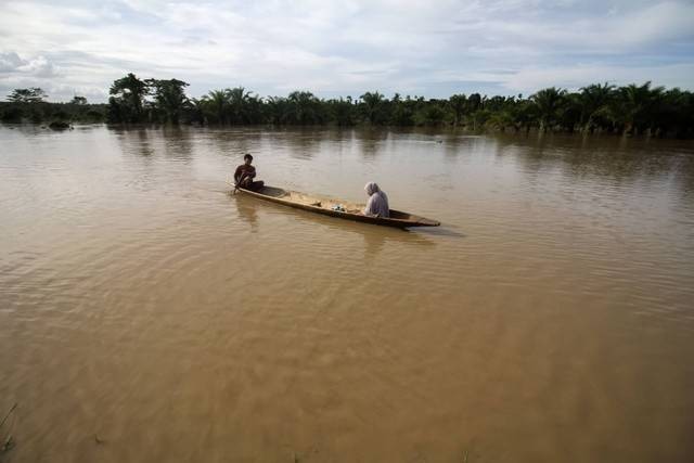 Warga menggunakan perahu melintas di tengah banjir yang merendam Desa Buket Linteueng, Kecamatan Langkahan, Aceh Utara, Aceh, Senin (23/1/2023). Foto: Rahmad/Antara Foto