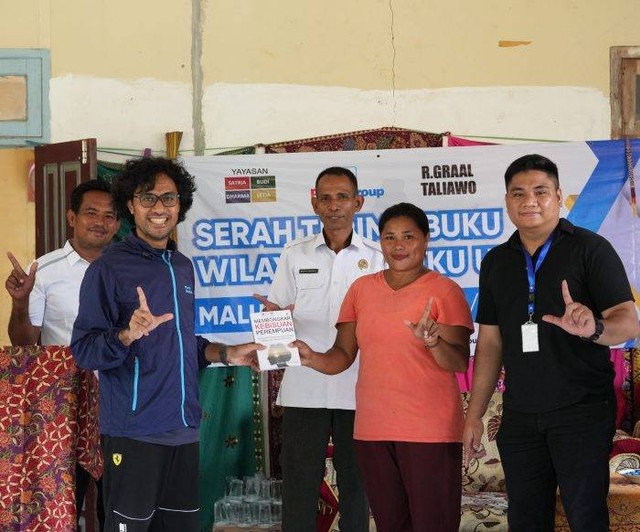 R Graal Taliawo menyerahkan buku kepada penggagas Literasi PERRI, Yulia Pihang, di Kantor Desa Saolat, Halmahera Timur, Maluku Utara. Foto: Istimewa