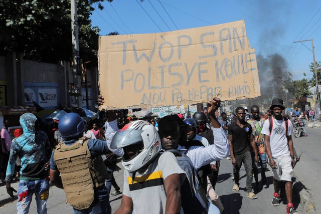 Seorang demonstran mengangkat poster bertuliskan: "Terlalu banyak darah polisi yang ditumpahkan. Kami tidak tahan lagi" selama protes atas pembunuhan polisi baru-baru ini oleh geng bersenjata, di Port-au-Prince, Haiti 26 Januari, 2023. Foto: Ralph Tedy Erol/REUTERS