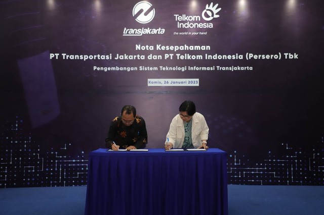 Proses penandatanganan nota kesepahaman kerja sama Telkom dan Transjakarta oleh PLT Direktur Enterprise and Business Service Telkom FM Venusiana R. (kanan) dan Direktur Utama Transjakarta M. Kuncoro Wibowo (kiri) pada Kamis (26/1). Foto: dok. Telkom Indonesia