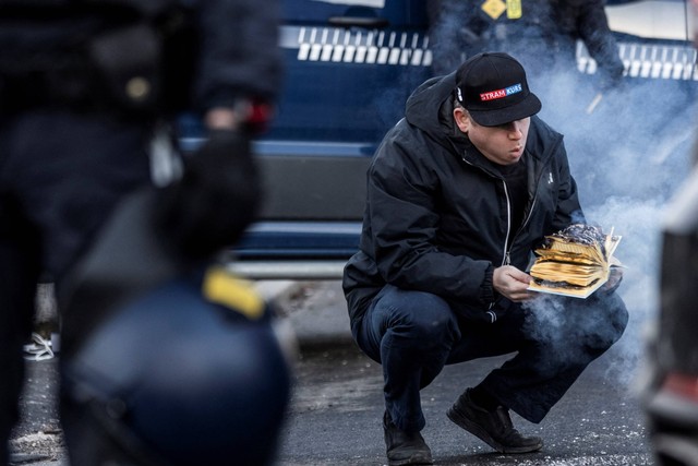 Politisi sayap kanan Rasmus Paludan membakar salinan Al-quran saat protes di depan kedutaan Turki di Kopenhagen, Denmark, Jumat (27/1/2023). Foto: Ritzau Scanpix/Olafur Steinar Gestsson via REUTERS