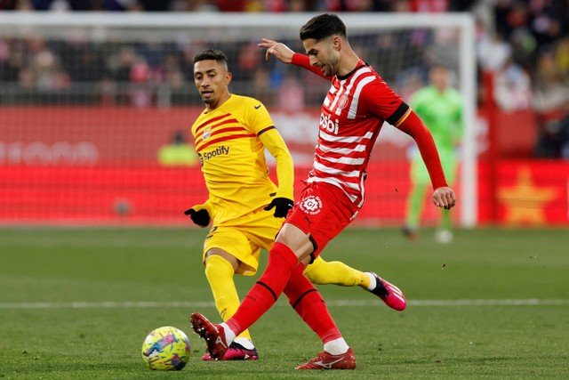 Pemain FC Barcelona Raphinha beraksi bersama pemain Girona Juanpe di Estadi Montilivi, Girona, Spanyol, Sabtu (28/1/2023). Foto: Albert Gea/REUTERS