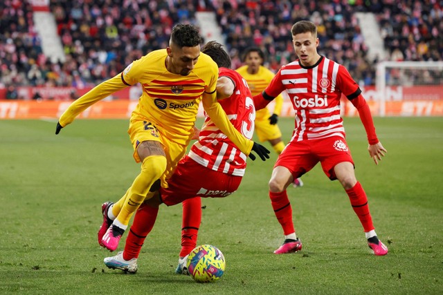 Pemain FC Barcelona Raphinha beraksi bersama pemain Girona Miguel Gutierrez di Estadi Montilivi, Girona, Spanyol, Sabtu (28/1/2023). Foto: Albert Gea/REUTERS