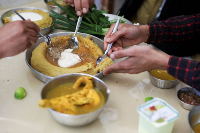 Pelanggan makan bubur, atau aseed, hidangan populer Yaman di Sanaa, Yaman. Foto: Khaled Abdullah/REUTERS