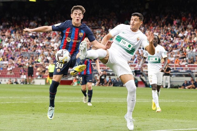 Pemain FC Barcelona Gavi beraksi bersama pemain Elche Diego Gonzalez di Stadion Camp Nou, Barcelona, Spanyol, Sabtu (17/9/2022). Foto: Albert Gea/REUTERS