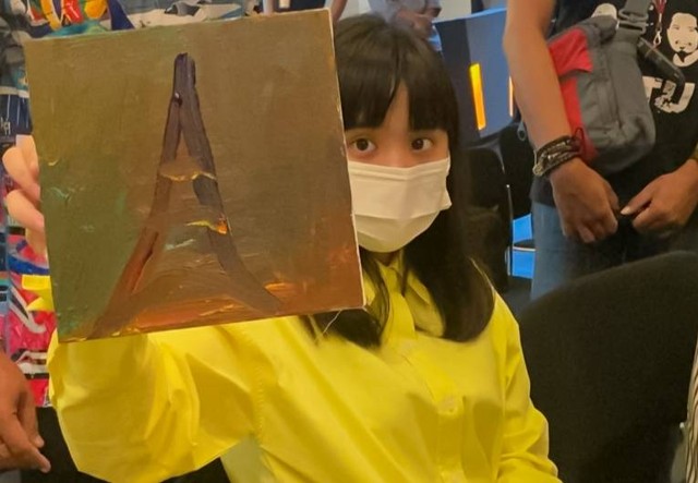 Celena menunjukkan karya lukisnya. Karya Celena bersama 2 seniman penyandang autisme lainnya dipajang Artotel TS Suite Surabaya.