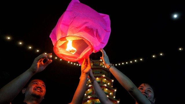 Dua orang pengunjung yang sedang bermain lampion di depan pagoda pada puncak perayaan cap go meh di Pulau Kemaro Palembang, Sabtu (4/2) Foto: abp/Urban Id