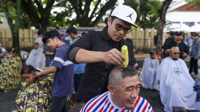 Warga melakukan aksi cukur rambut botak bareng dalam peringatan Hari Kanker Sedunia (World Cancer Day) 2023 di area Car Free Day Banda Aceh, Ahad (5/2). Foto: Suparta/acehkini