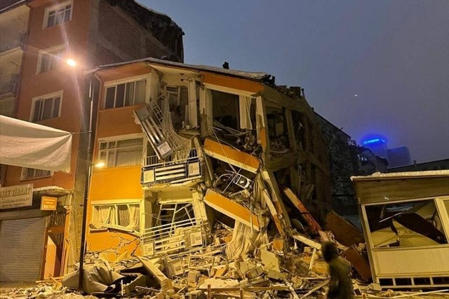 Seorang pria berjalan melewati bangunan yang runtuh setelah gempa bumi di Malatya, Turki, Senin (6/2/2023). Foto: Depo/via REUTERS