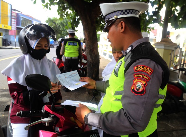 Anggota Polisi Lalu Lintas memberikan surat peringatan kepada pengendara sepeda motor saat operasi keselamatan dalam berlalu lintas di Kota Ternate, Maluku Utara, Selasa (7/2/2023). Foto: ANTARA FOTO/Andri Saputra