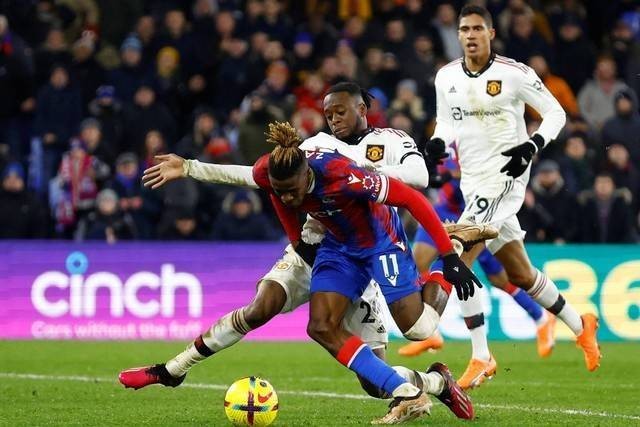 Pemain Manchester United Aaron Wan-Bissaka berebut bola dengan pemain Crystal Palace Wilfried Zaha pada pertandingan lanjutan Liga Inggris di Stadion Selhurst Park, London, Inggris, Rabu (18/1/2023). Foto: Peter Cziborra/REUTERS