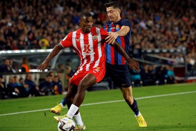 Pemain Almeria Sergio Akieme beraksi dengan pemain FC Barcelona Robert Lewandowski di Stadion Camp Nou, Barcelona, Spanyol, Sabtu (5/11/2022). Foto: Albert Gea/REUTERS