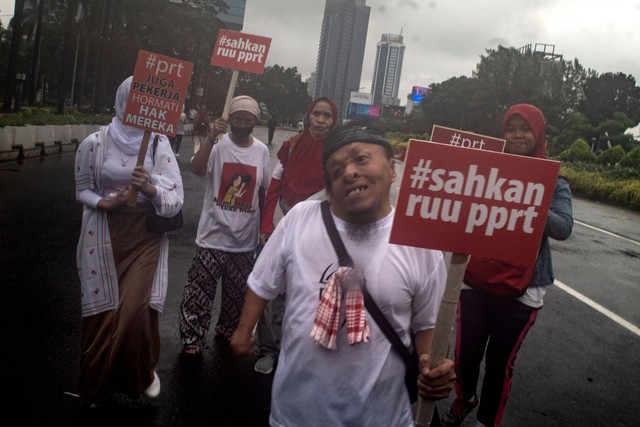 Sejumlah PRT membawa poster saat mengikuti acara Pawai Dukung Percepatan Pengesahan RUU PPRT bersama Komnas HAM di kawasan Sudirman-Thamrin, Jakarta, Minggu (12/2/2023). Foto: Muhammad Adimaja/Antara Foto