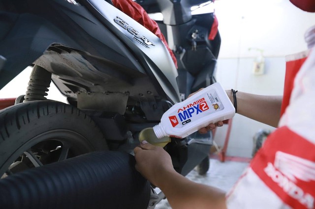 Teknisi AHASS melakukan penggantian pelumas sepeda motor Honda menggunakan AHM OIL MPX2 dengan ukuran 0,65L. Foto: Dok. Astra Kalbar