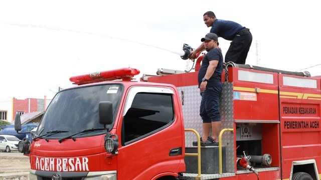 Pj Bupati Aceh Besar Muhammad Iswanto memimpin kegiatan pembersihan Pasar Lambaro dari atas mobil damkar, Ahad (12/2/2023). Foto: Dok. Pemkab Aceh Besar